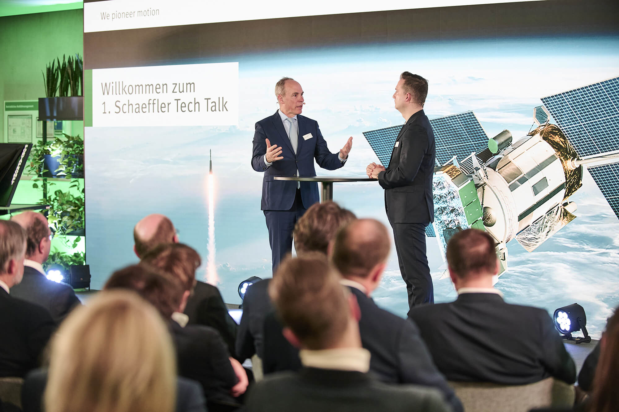 Stage view of the 1st Schaeffler Tech Talk with Christoph Keese and Matthias Wachter in front of the audience and a space-themed backdrop.