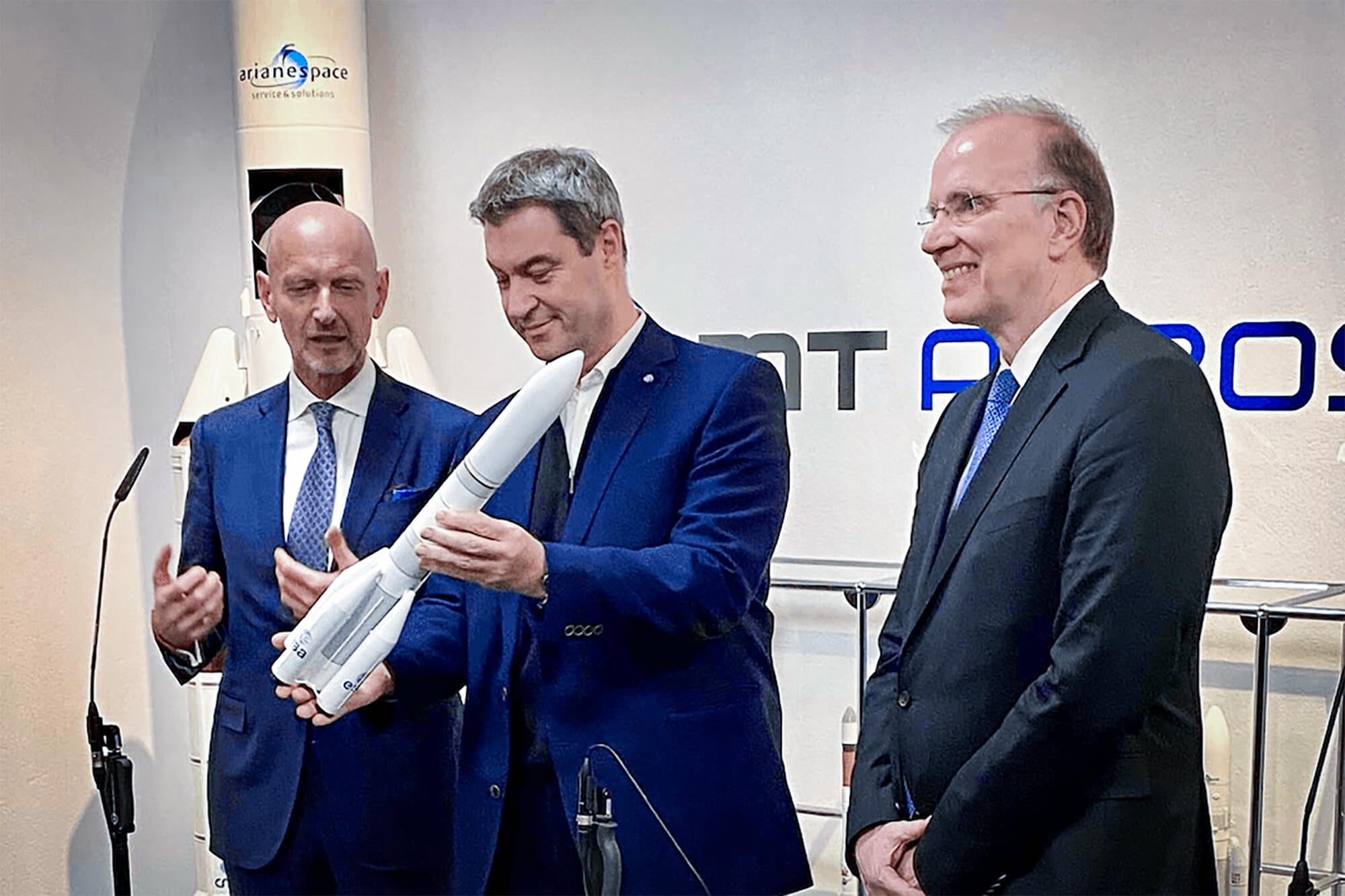 Markus Söder präsentiert ein Ariane-Raketenmodell bei einer Aerospace-Veranstaltung, neben ihm stehen Hans Steininger und Marco Fuchs.