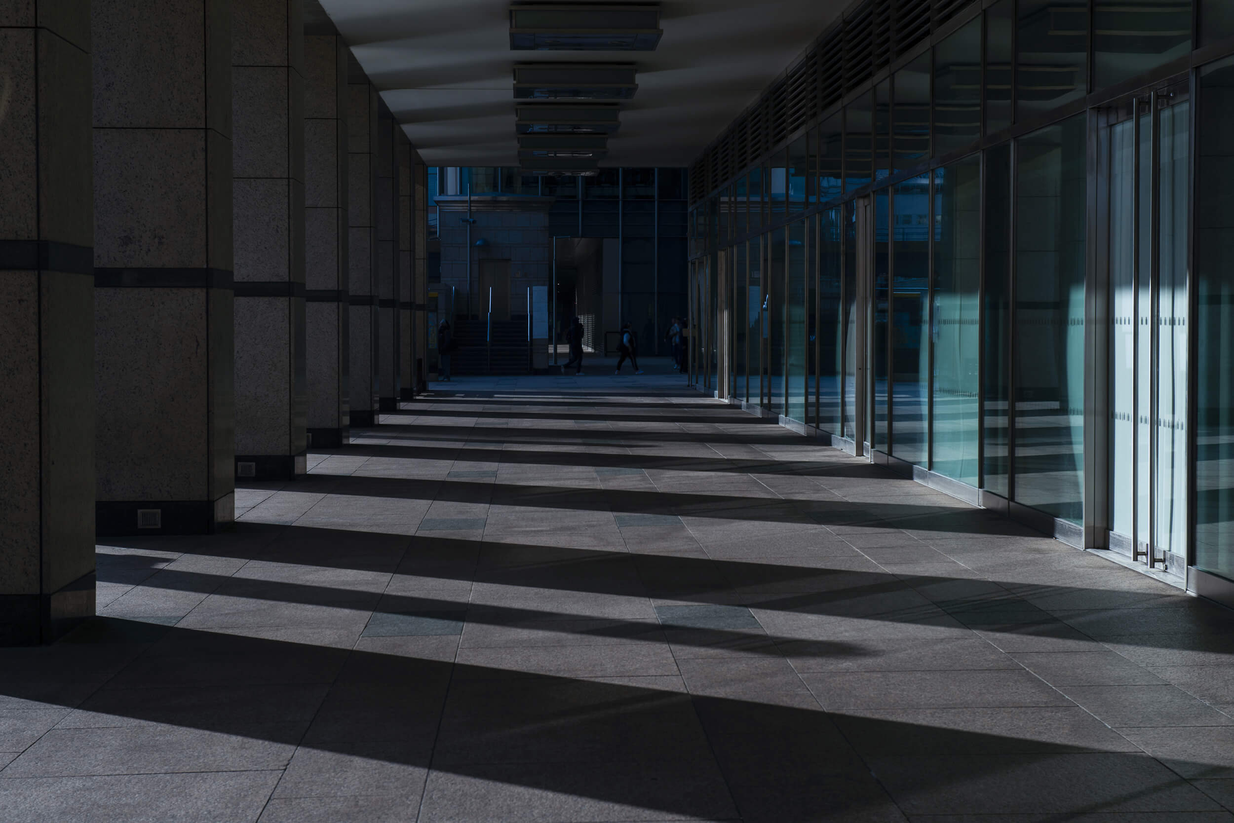 Long colonnade of a modern office complex with glass facades and rhythmic light stripes
