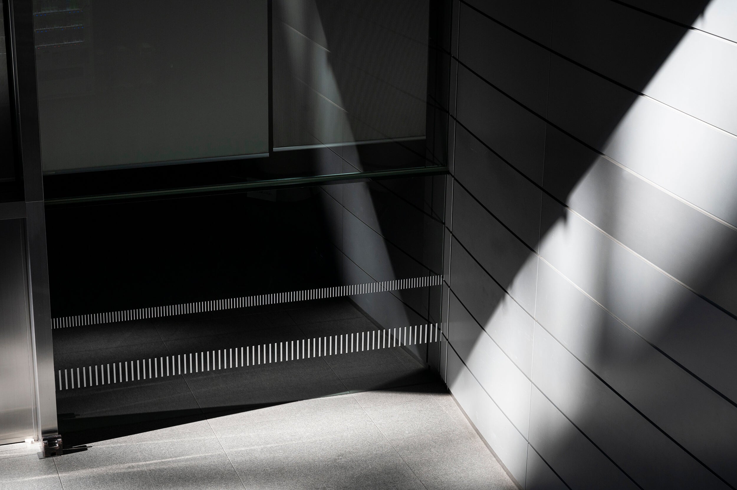 Minimalist office building entrance with geometric light and shadow patterns
